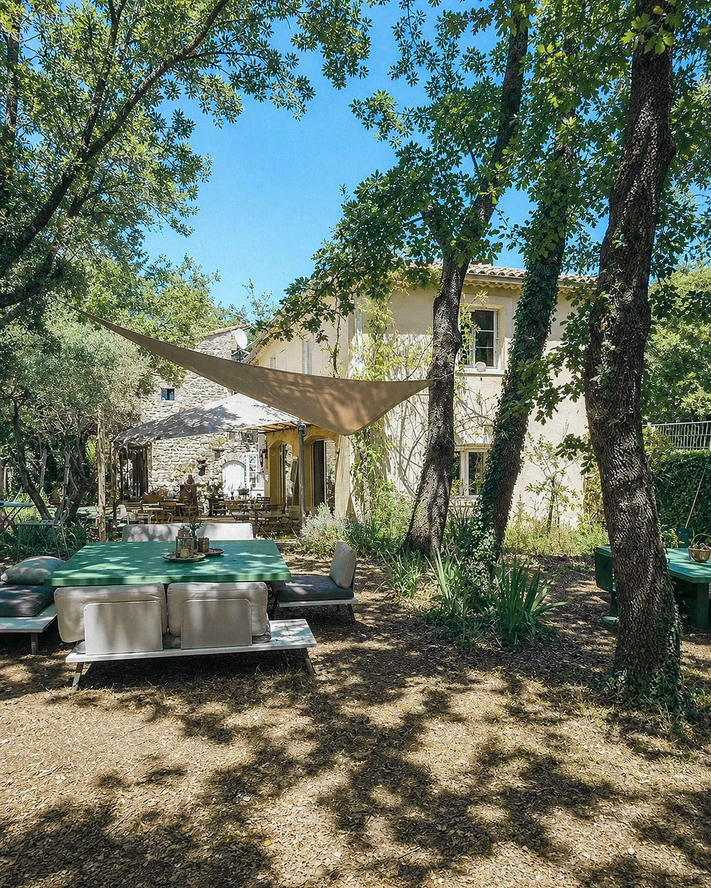 L'été aux Buisses : tables sous la canopée, ombre du feuillage.